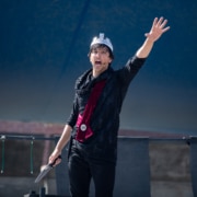 An actor raises his arm while performing in Macbeth for Shakespeare in the Parking Lot