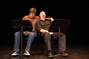 Two actors sit close together on chairs in Insectivore