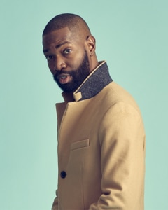 Headshot of Tarell Alvin McCraney standing in front of a blue background