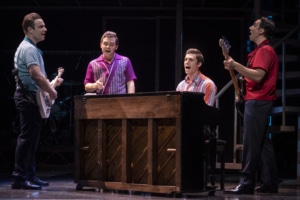 Four actors sing around a piano in Jersey Boys