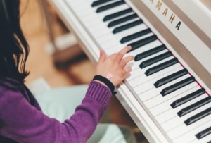 A child sits with one hand on the keys of a keyboard