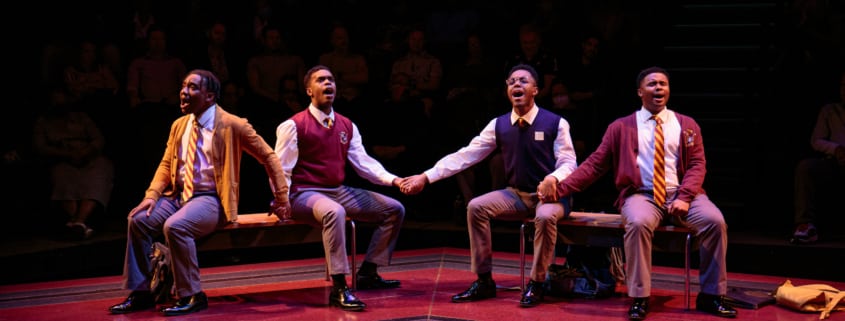 The cast of Choir Boy sits on benches holding hands