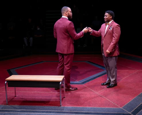 Two males shake hands in the middle of the stage