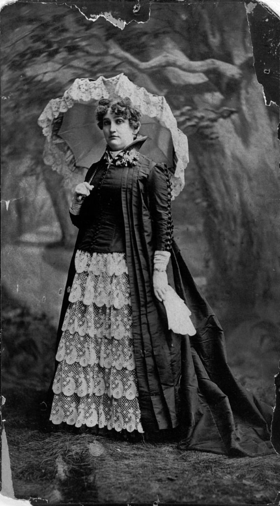 An old photograph of Mattie Silks wearing an elaborate gown and holding a lace parasol