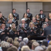 The Kantorei choir holds music books while singing onstage