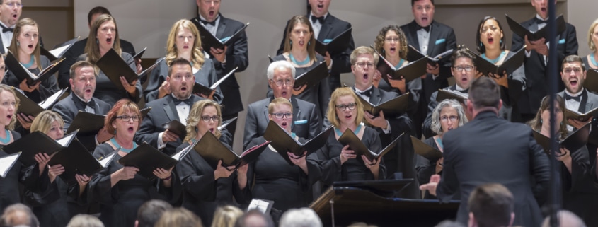 The Kantorei choir holds music books while singing onstage