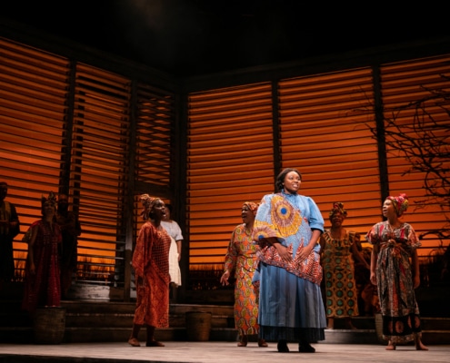 A group of women dressed in traditional African clothing sing onstage in The Color Purple.