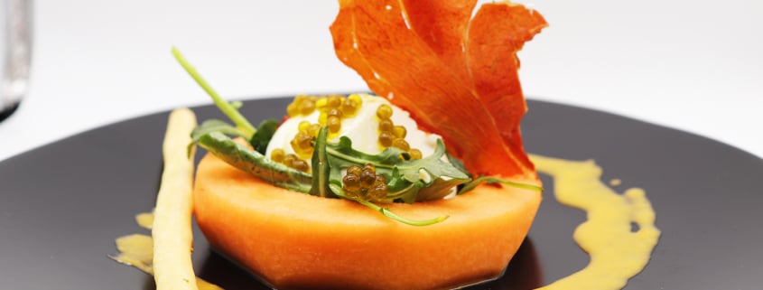 A cantaloupe and burrata salad is beautifully presented on a plate