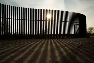 The sun shines through the slats of the border wall between Texas and Mexico