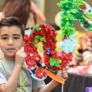 A child poses with his craft at the Dia del Nino celebration