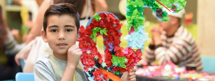 A child poses with his craft at the Dia del Nino celebration