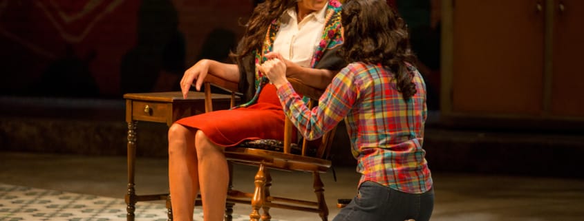 A woman kneels next to a woman sitting in a rocking chair