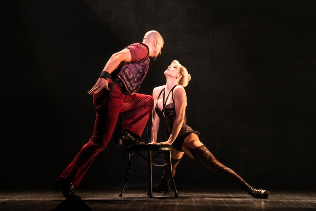 Dancers lean into one another over a chair in a tango