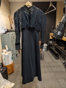 The Wicked Witch of the West dress hangs in the costume shop