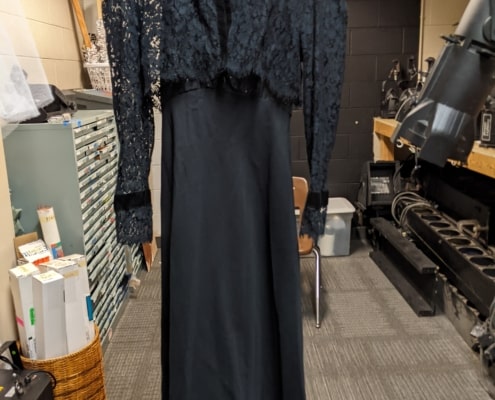 The Wicked Witch of the West dress hangs in the costume shop