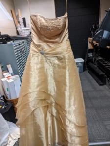 A yellow dress hangs in the costume shop