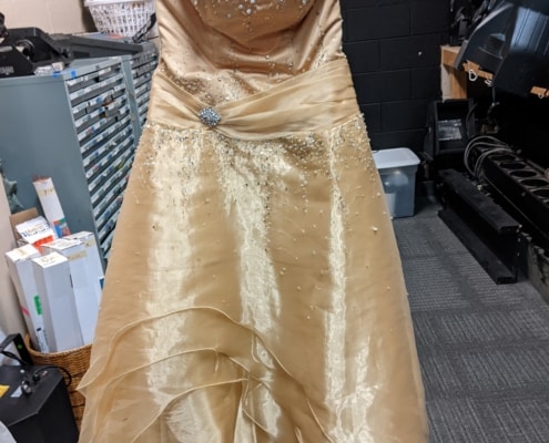 A yellow dress hangs in the costume shop