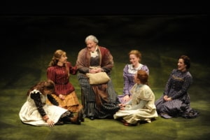 A woman is seated on a chair surrounded by young women