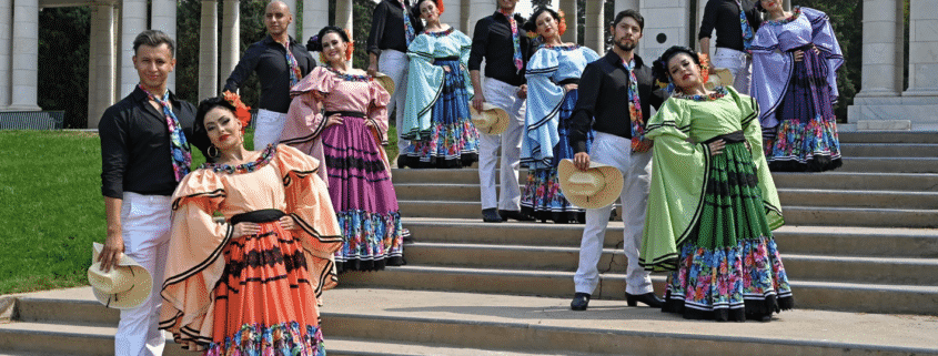 A group of dancers pose in colorful costumes