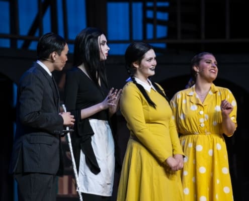 The Addams Family stands together onstage