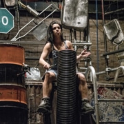 A woman performing in STOMP seated while drumming