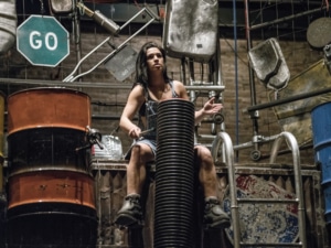 A woman performing in STOMP seated while drumming