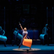 The cast of STOMP performs with large buckets