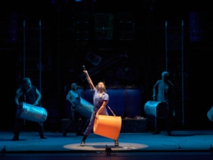 The cast of STOMP performs with large buckets