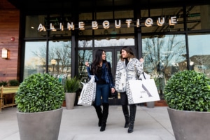 Two women leave Aline Boutique with shopping bags