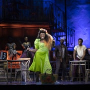 A woman dances center stage while others look on in Hadestown