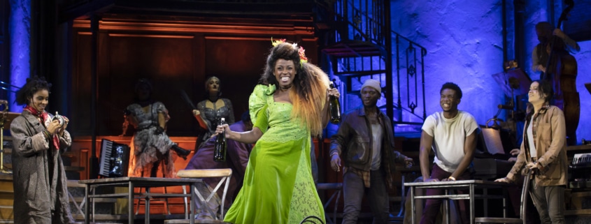 A woman dances center stage while others look on in Hadestown