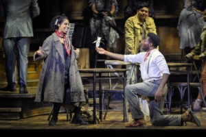 A man kneels reaching towards a woman in Hadestown