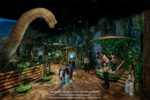 People walk through an exhibit with dinosaurs and greenery