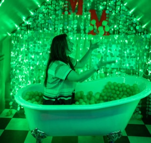 A woman sits in a bathtub lit up with glowing green lights