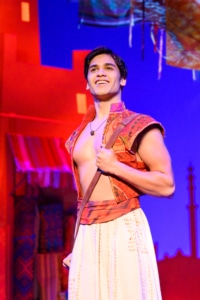 Aladdin stands proudly, a bag slung over his shoulder