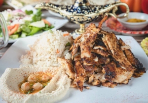 A plate of meat with hummus and rice