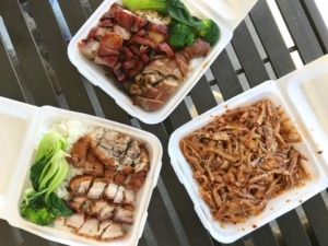 Three takeout containers with different Chinese dishes inside