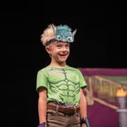 A child wearing a monster costume smiles onstage