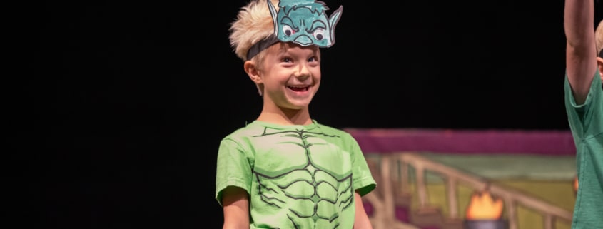 A child wearing a monster costume smiles onstage