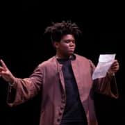 A DCPA education student reads from a piece of paper onstage