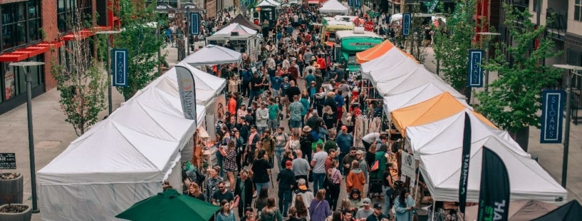 A large crowd of people walks through a market