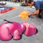 A man continues his chalk art of hungry hungry hippos