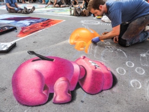 A man continues his chalk art of hungry hungry hippos