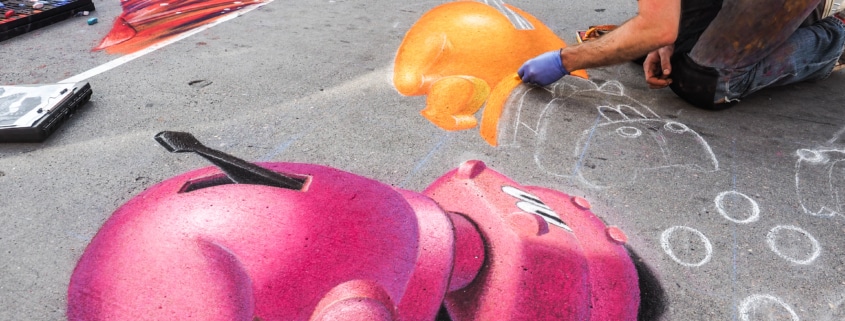 A man continues his chalk art of hungry hungry hippos