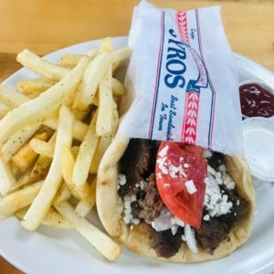 A gyro wrapped in paper on a plate with fries