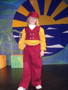 A young girl wearing a costume poses onstage