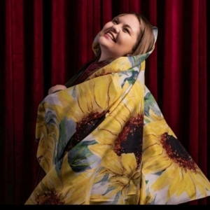 A woman smiles wrapped in a sunflower printed blanket