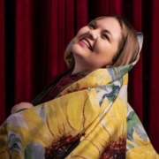 A woman smiles wrapped in a sunflower printed blanket