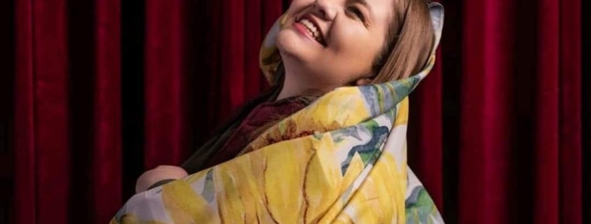 A woman smiles wrapped in a sunflower printed blanket