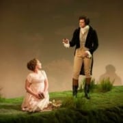 A young woman kneels while a man stands over her, speaking in Sense and Sensibility The Musical.